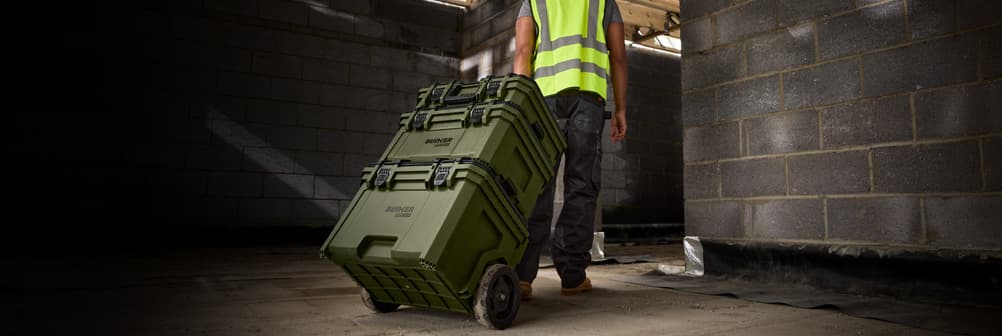 Tradesman wheeling stacked BUNKER Load-Up tool boxes through a building site