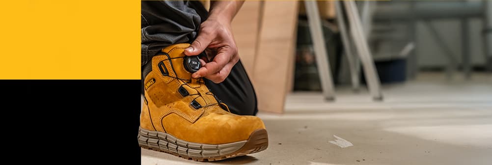 A DeWalt Lancaster honey boot on a work site with BOA technology - a hand turns the dial
